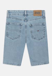 Jasnoniebieskie szorty dżinsowe z dwoma tylnymi kieszeniami, brązową skórzaną naszywką z napisem "TOMMY HILFIGER" oraz subtelnymi detalami stębnowania.