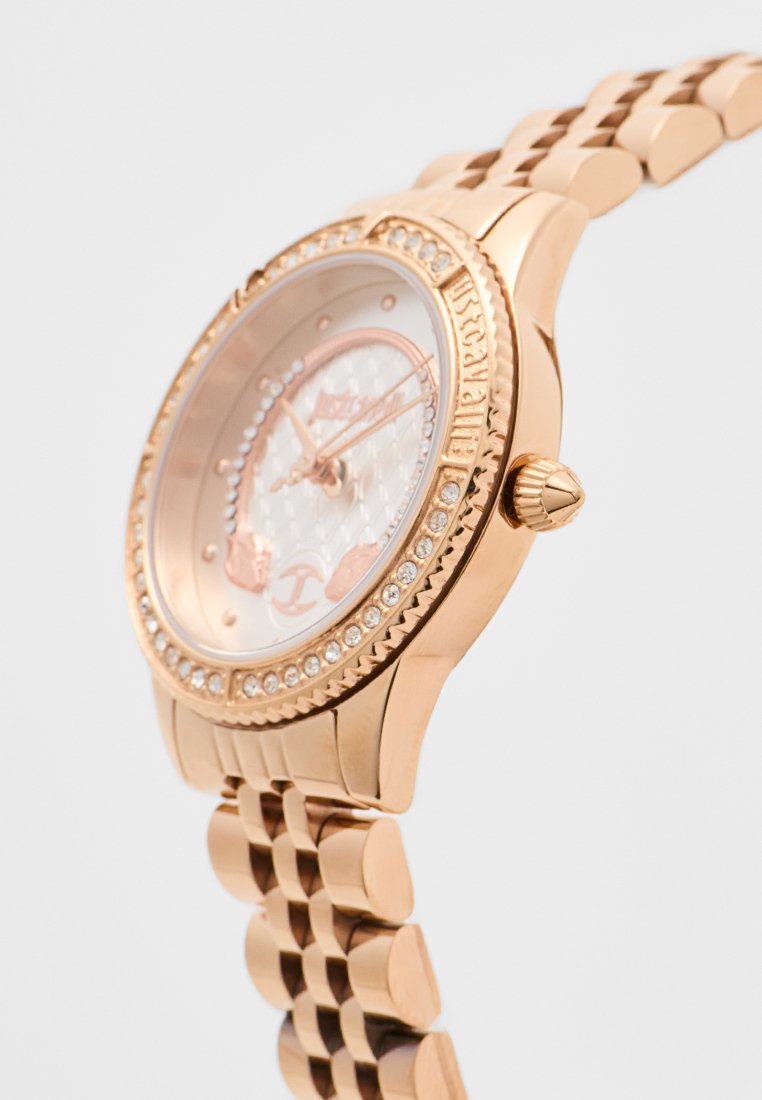 Montre-bracelet en or rose avec un cadran incrusté de cristaux, un cadran à motif et un bracelet en métal à maillons, présentée en gros plan sous un angle.