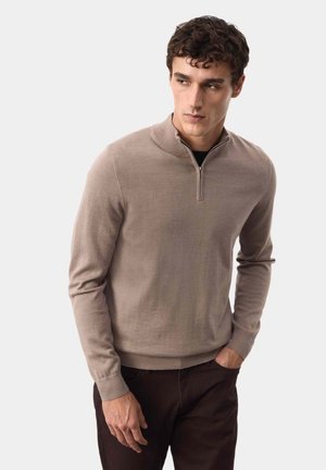 Pullover beige a maniche lunghe in maglia con colletto a mezza zip, polsini a coste e texture liscia, abbinato a pantaloni marrone scuro.