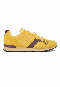 Baskets basses jaunes et violettes avec lacets blancs, panneaux en mesh et semelle beige, arborant le logo Tommy Hilfiger sur le côté.