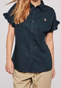 Mörk marinblå kortärmad skjorta med volangärmar, knapp-fram design och en liten broderad detalj. Tillverkad av mjukt och slätt tyg.