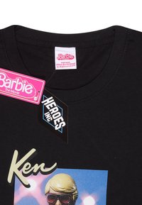 Schwarzes Baumwoll-T-Shirt mit einem grafischen Motiv von Ken aus dem Barbie-Film, hervorgehoben durch einen bunten Hintergrund und auffälligen Text. Etiketten sind enthalten.