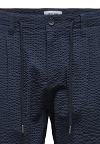 Shorts bleu marine avec un motif en nid d'abeille texturé, dotés d'une fermeture à bouton, d'un cordon de serrage et de poches latérales pour plus de commodité.