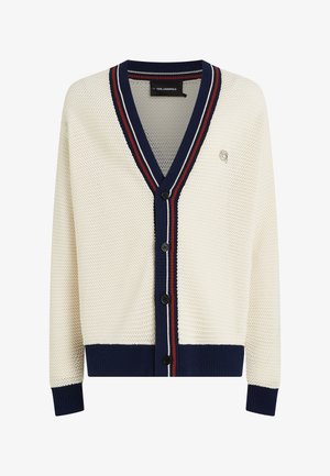 Strikket cardigan i cremefarve med V-hals, marineblå ribkant og røde og hvide striber. Indeholder fem sorte knapper og tekstureret mønster.