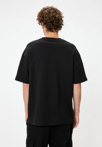 Mustat lyhythihaiset t-paidat, joissa on pyöreä kaula-aukko, valmistettu pehmeästä kankaasta. T-paidassa on rento istuvuus ilman näkyviä logoja tai kuvioita.