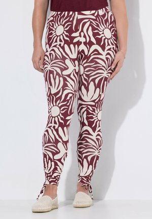 Leggings med bordeaux og hvide abstrakte blomster- og solmønstre, med justerbare snore ved anklerne, båret med beige vævede slip-on sko.