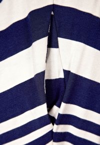 Lähellä tummansinistä ja valkoista raidallista kangasta, jossa on keskisauma, joka luo pystysuoran taitteen.