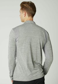 Langärmliges Hemd in hellgrau mit strukturiertem Stoff. Verfügt über einen Stehkragen und kontrastierende graue Akzente an den Schultern. Minimalistisches Design.