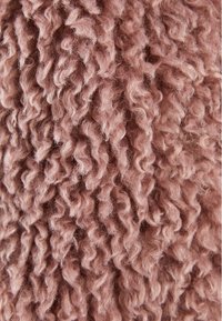 Texturerad tyg i mjuk rosa nyans; har vridna, plush fibrer som skapar ett vågigt, fluffigt utseende. Lämplig för varma textilier eller m öbelklädsel.