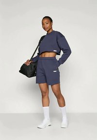 Marine kratek pulover in ujemajoče kratke hlače iz mehkega blaga, z elastičnim pasom in stranskimi žepi, v kombinaciji z belimi supergami.