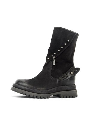 Botte en cuir noire mi-mollet avec semelle robuste, clous décoratifs argentés, fermeture éclair et détail de sangle à boucle sur le côté.