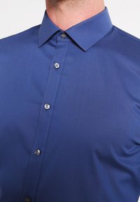 Blauw button-up shirt, gladde textuur, spitse kraag, zes knopen aan de voorkant met contrasterende zilveren hardware, getailleerde pasvorm.