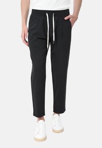 Pantaloni tapered neri realizzati in un materiale morbido, con una vita elastica dotata di coulisse, tasche laterali e una vestibilità rilassata.