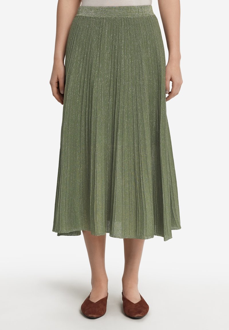 Fållad midiklänning i ljusgrön med subtil glans. Elastisk midja, flödande form och en mjuk textur. Skorna är bruna lägenheter.