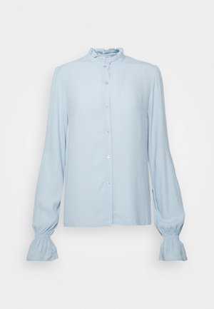 Blusa azzurro chiaro a maniche lunghe con colletto e polsini arricciati, chiusura frontale con bottoni e vestibilità ampia.