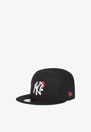 Schwarze Snapback-Cap mit einem weißen NY-Logo, das einen roten Weihnachtsmannhut trägt. Sie hat eine grüne Unterseite des Schirms und rot/grüne Akzente an der Seite.