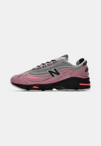 New Balance tenisice u ružičastoj, sivoj i crnoj boji, s mrežastim i sintetičkim gornjim dijelom, imaju debeli potplat i kontrastne naglaske u narančastoj boji.