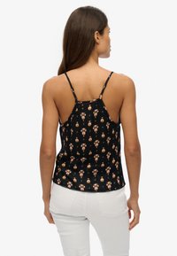 Top de tirantes negro con estampado floral, con tirantes finos y borde ondulado. Material ligero con un corte relajado, que presenta colores vibrantes.