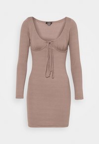 Abito a maniche lunghe a coste di un colore marrone tenue, con scollatura a barca e dettaglio con nodo frontale. Design aderente, lunghezza al ginocchio.