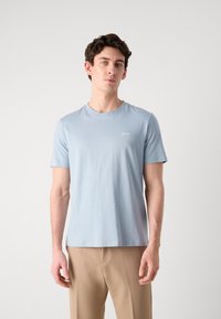 T-shirt in cotone azzurro chiaro con scollo rotondo e maniche corte, caratterizzato da un piccolo logo bianco "HUGO" sul lato sinistro del petto.