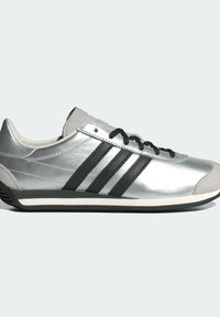 Silver leather sneaker with black stripes, lace-up design, rubber sole, and gray suede accents. Rounded toe, sleek silhouette.