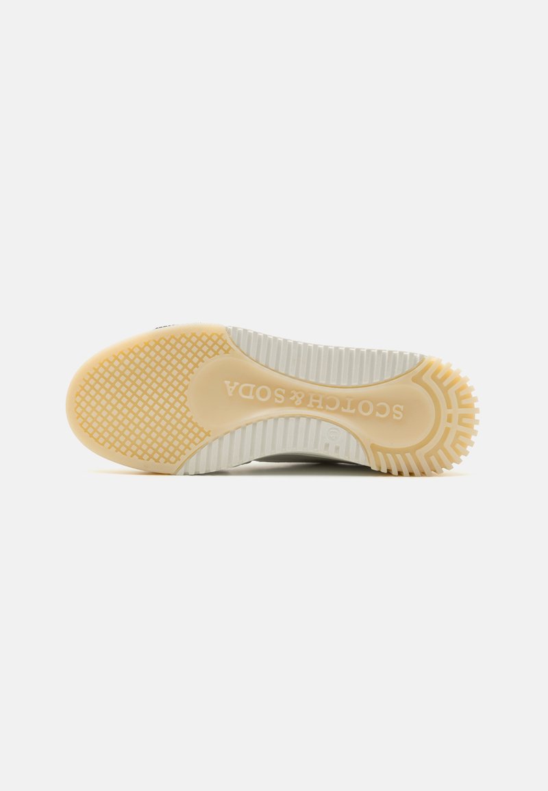 Graue Sport-Schuhsohle mit einer strukturierten Gummioberfläche, die ein beiges Traktionsmuster aufweist und in das den Markennamen "Soda" eingeprägt ist.