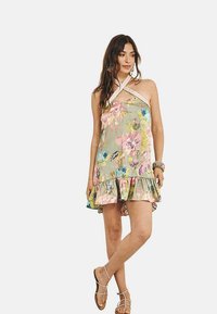 Vestido halter floral con una base verde claro, vibrantes flores rosas y azules, dobladillo con volantes y detalle de encaje en el escote.