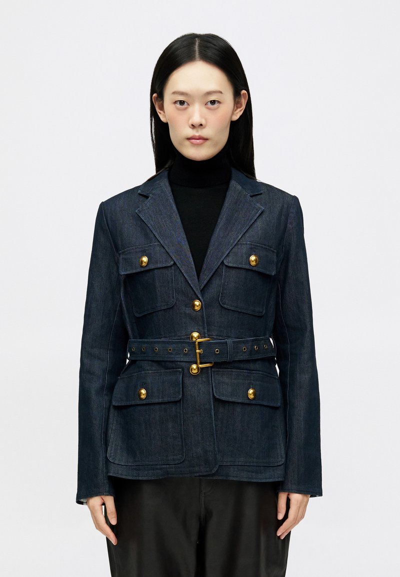 Blazer in denim blu scuro con bottoni dorati, quattro tasche frontali e una cintura coordinata con fibbia e fori per la regolazione.