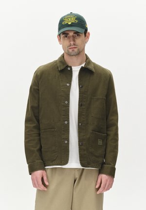 Olive green jacket, cotton material, buttoned front, two front pockets, paired with a white shirt and light beige pants, simple design.