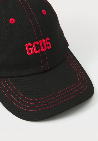 Casquette noire avec logo "GCDS" brodé en rouge, couture rouge contrastante et visière courbée. Présente des trous de ventilation et une forme structurée.
