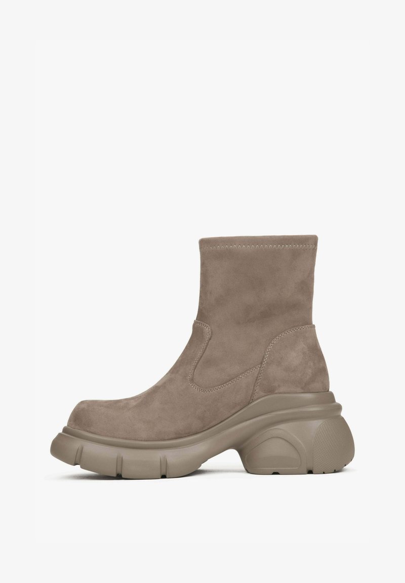 Jasnobrązowe zamszowe botki za kostkę z grubą, teksturowaną podeszwą platformową i elastycznymi bocznymi panelami. Charakteryzują się estetycznym wykończeniem szwu na górze.