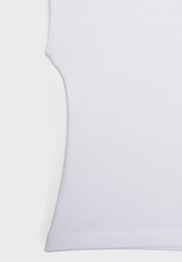 Gros plan sur un vêtement blanc uni sans manches avec un tissu lisse et des coutures propres le long des bords, sur fond blanc.