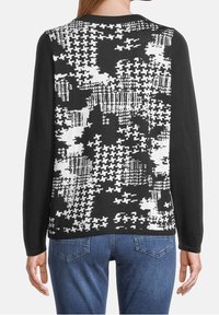 Svart tröja med abstrakt vitt mönster på baksidan. Långärmad, rund hals, strukturerad tyg och minimalistiska design detaljer.