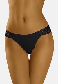 Thong in pizzo nero con corpo in tessuto morbido, caratterizzato da una vita decorativa in pizzo con intricate decorazioni a intaglio e bordi ondulati.