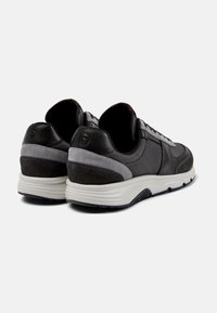 Men's sneakers featuring a mix of black leather and grey suede, with a textured finish, cushioned sole, and contrasting accents on the heel.