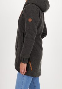 Ciemnoszara kurtka z kapturem, z prążkowanymi mankietami, dwoma kieszeniami po bokach oraz brązową skórzaną naszywką z logo na lewym rękawie. Gładka tekstura, fason o długości do połowy.