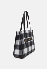 Sac en laine à carreaux noir et blanc avec des poignées en cuir noir et une poche zippée à l'avant. Forme structurée, texture douce et accent en doré sur la fermeture éclair.