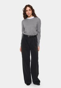Grauer Strickpullover mit Rundhalsausschnitt, kombiniert mit hochtaillierten schwarzen weitem Jeans und einem schwarzen Gürtel, der eine glatte Textur und einen lässigen Schnitt aufweist.