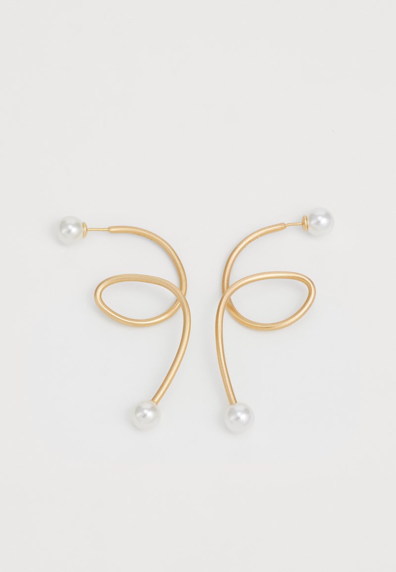 Pendientes de color dorado con un diseño fluido y en bucle, que presentan dos perlas blancas y redondas en los extremos. Textura de metal suave, forma moderna.