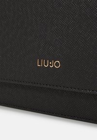 Portafoglio nero con texture, bordi cuciti e un logo dorato "LIU·JO" ben in evidenza. Il materiale sembra sintetico con una finitura a motivo.
