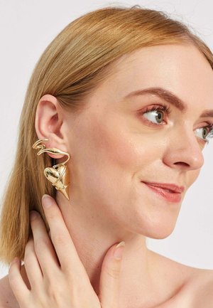 Zlaté náušnice so točnou drôtovou konštrukciou a detailom srdca a hrotu. Hladký, lesklý povrch zvýrazňuje ich zložitý tvar.