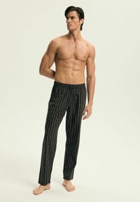 Męskie czarne piżamy w kratę z elastycznym pasem i sznurkiem, charakteryzujące się luźnym krojem i gładką teksturą materiału.