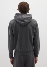 Felpa grigia realizzata in materiale morbido, con cappuccio regolabile, polsini a coste e una vestibilità affusolata con un dettaglio della vita.