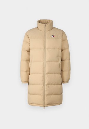 Doudoune beige avec un col haut, présentant une fermeture éclair intégrale et un motif matelassé horizontal. Patch logo sur le côté supérieur gauche.