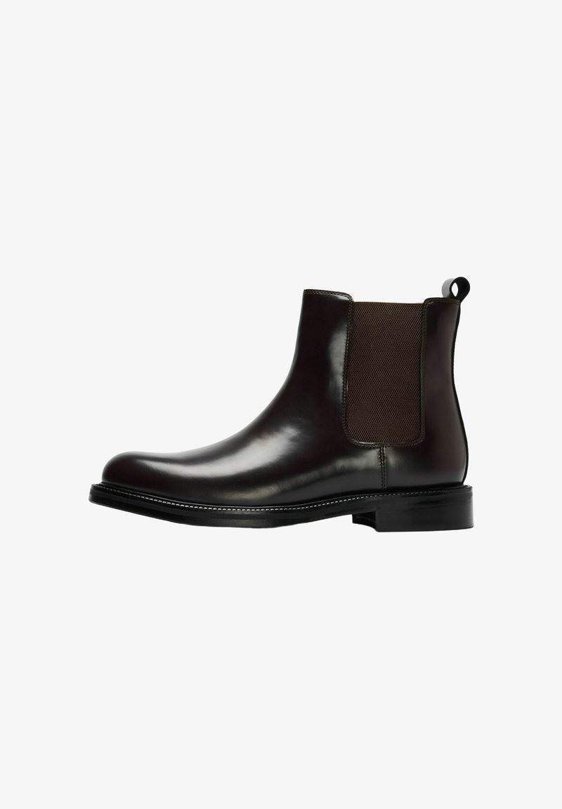 Bottine Chelsea en cuir noir avec panneau latéral élastique, languette à l'arrière, et petit talon empilé.