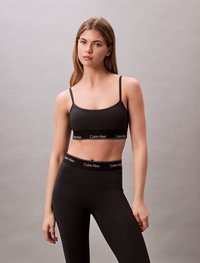 Black bralette and high-waisted leggings, both made of stretchy fabric. Bralette features thin straps; waistband has a branded black accent.
