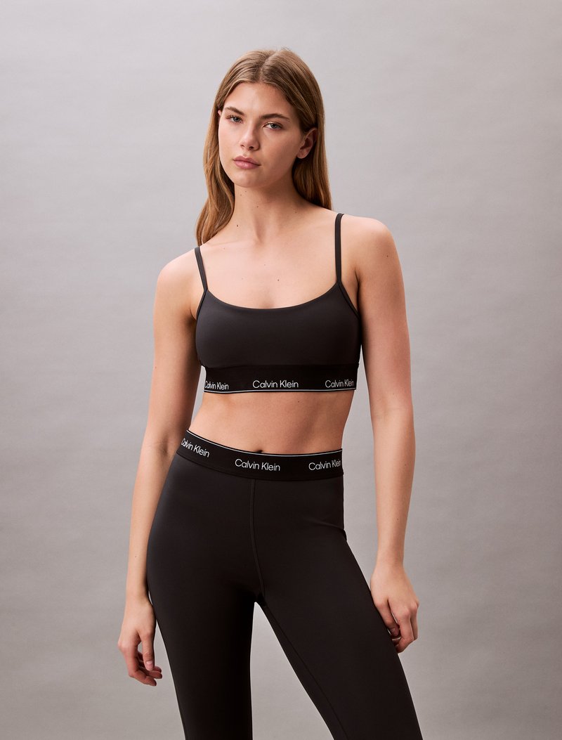 Black bralette and high-waisted leggings, both made of stretchy fabric. Bralette features thin straps; waistband has a branded black accent.