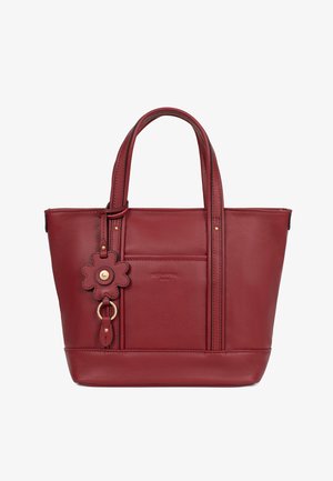 Rode leren totebag met dubbele handvatten, voorvak en een eraan bevestigde sleutelhanger in bloemvorm met gouden accenten.