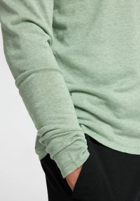 Ljust grön långärmad skjorta i mjukt, strukturerat tyg, med uppvikkta ärmar och avslappnad passform. Matchad med svarta byxor.