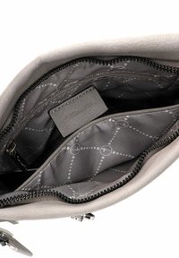 Light gray handbag interior with a smooth texture, zip closure, and printed fabric lining featuring a geometric design and brand label.